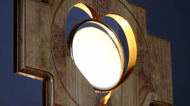 wooden ostensory with lit up sacramental bread in center