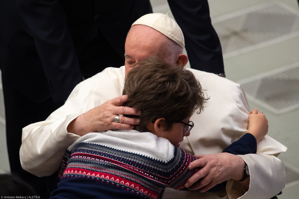 a child embraces Pope Francis