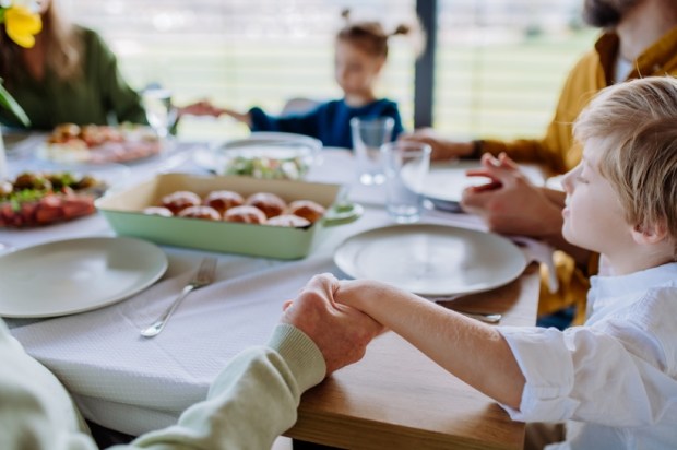 Close-up of family holding hands, praying before Easter lunch.