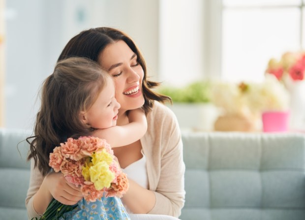 Child daughter congratulates mom and gives her flowers.