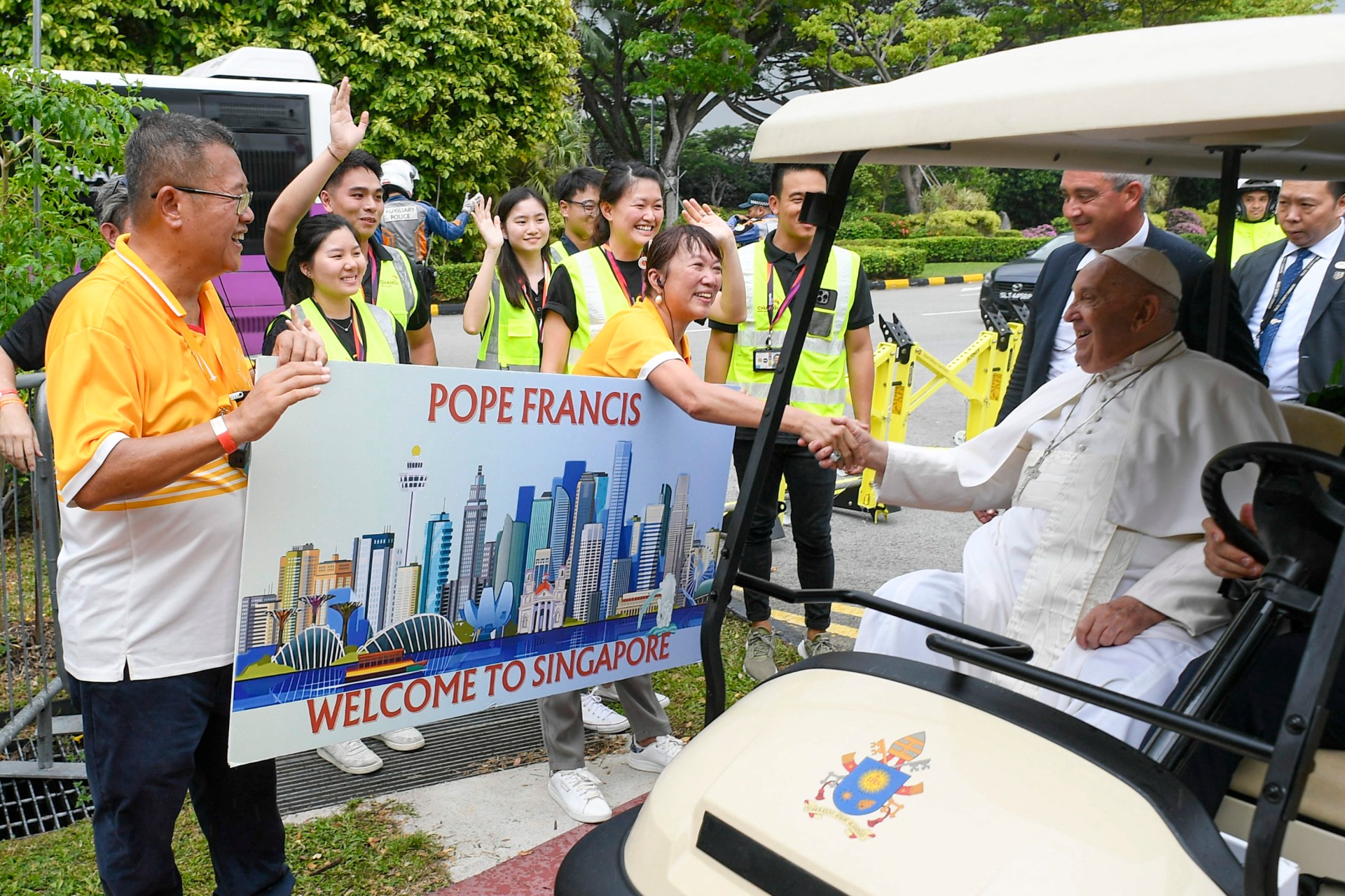 Pope Francis (2nd R) greets Catholic faithful welcoming him with a banner after his arrival in Singapore. Pope Francis touched down in Singapore on September 11, the last stop of a four-nation Asia-Pacific trip